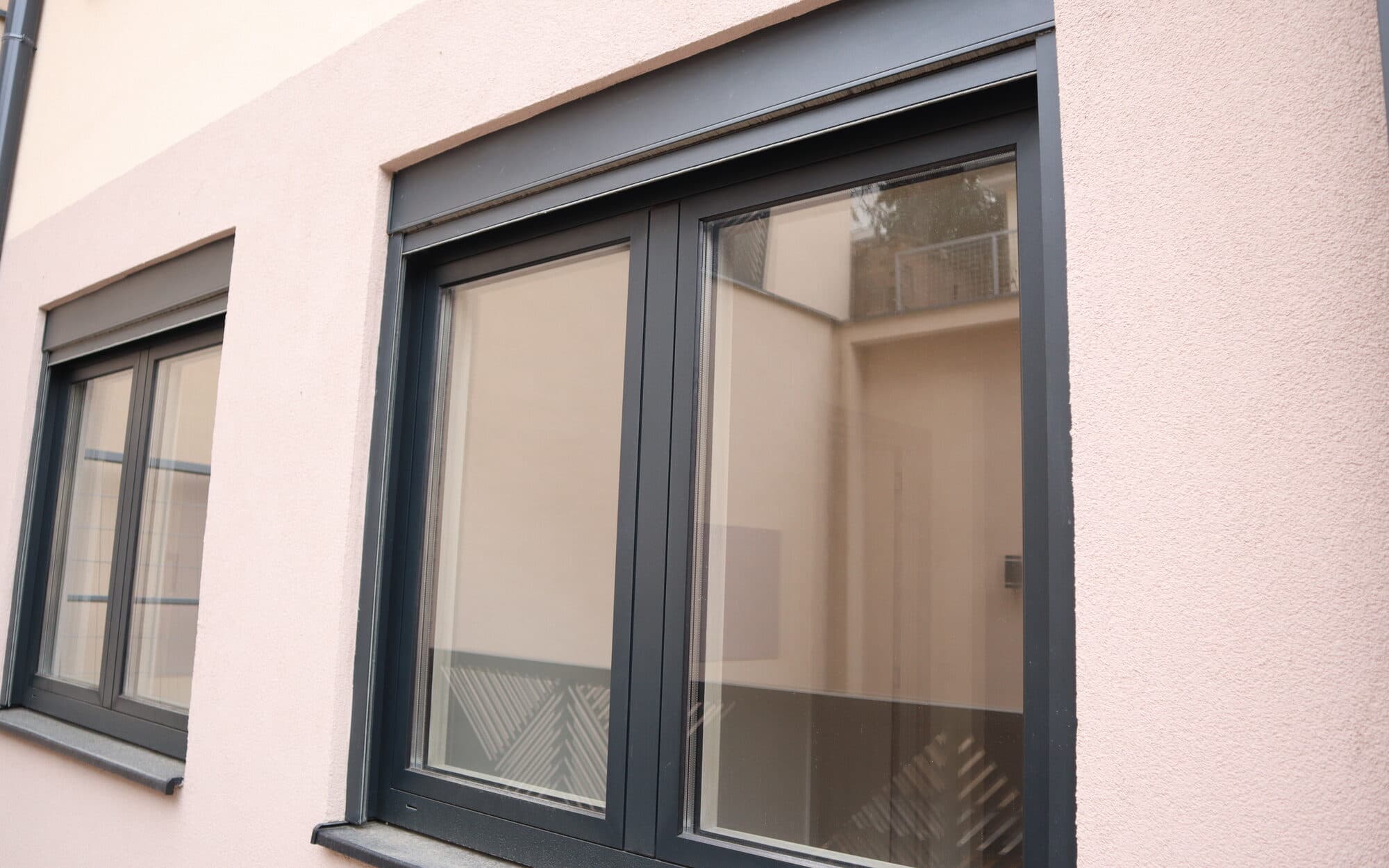Anthrazitfarbene Alufenster in einer verputzten Fassade, von Ading montiert