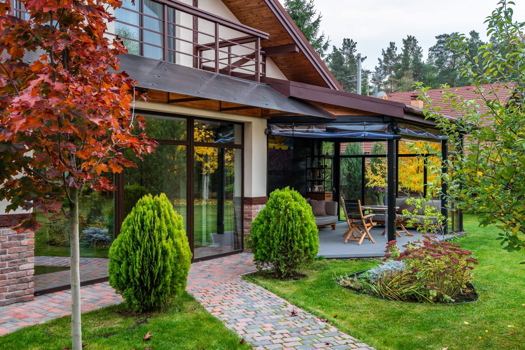 Terrassenüberdachung aus dunklem Metallrahmen mit Glaselementen an einem Wohnhaus